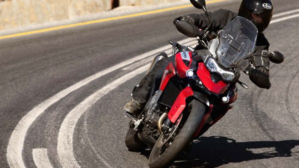 Tiger 900 Vermelha com piloto em cima acelerando na estrada de asfalto.